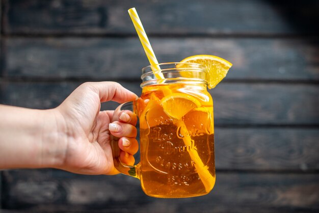 Suco de laranja fresco de vista frontal dentro de uma lata em um coquetel com foto colorida de fruta escura