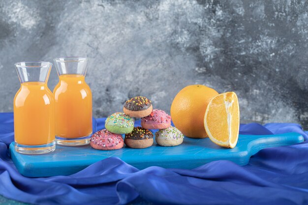 Suco de laranja fresco e frutas com biscoitos caseiros na placa de madeira azul.