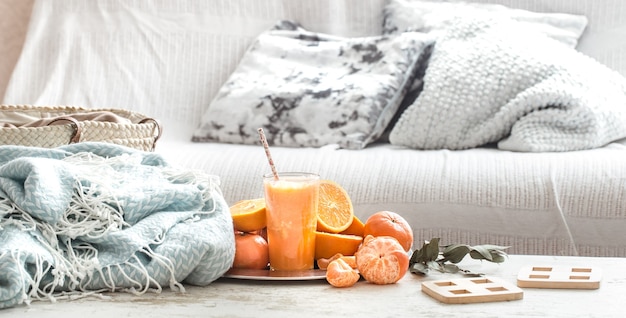Suco de laranja natural no interior da casa, com manta turquesa e cesta de frutas