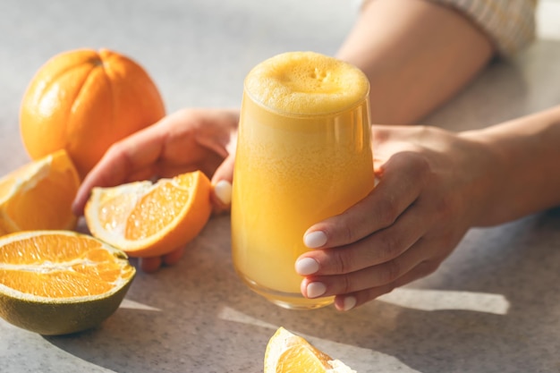 Suco de laranja recém-espremido em mãos femininas de perto