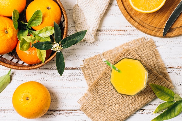 Suco de laranja refrescante ao lado do cesto cheio de laranjas