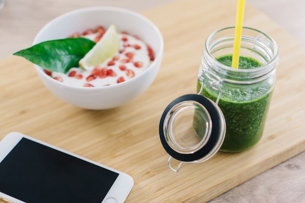 Suco verde ao lado tigela de cereais com iogurte