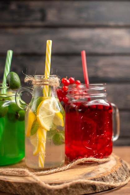 Sucos naturais de frutas orgânicas em garrafas servidas com tubos em uma tábua de madeira sobre uma mesa marrom