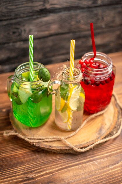 Sucos naturais de frutas orgânicas em garrafas servidas com tubos em uma tábua de madeira