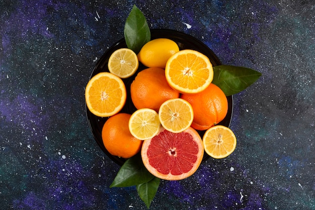 Suculentas frutas frescas inteiras ou meio cortadas sobre mesa escura.