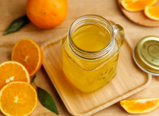 Sumo de laranja e laranjas na mesa de madeira retro