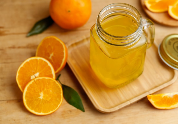 Sumo de laranja e laranjas na mesa de madeira retro