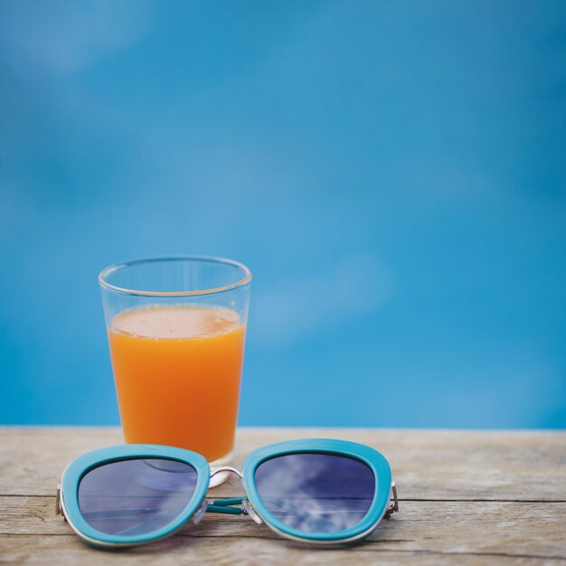 Superfície com bebida e óculos de sol azuis