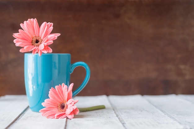 Superfície de madeira com caneca azul e flores decorativas