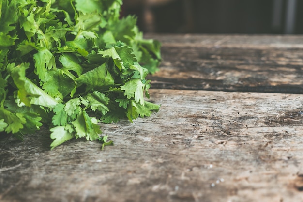 Superfície de madeira com espaço para texto com folhas de salsa verde ao lado