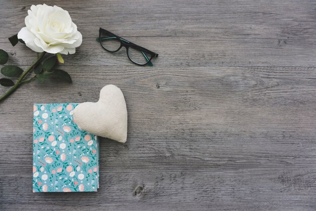 Superfície de madeira com flor branca, livro e coração