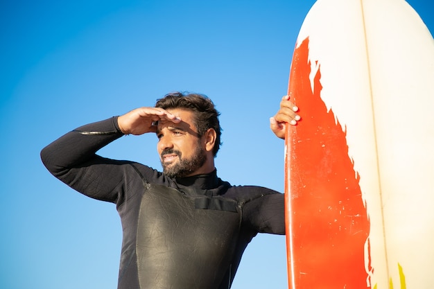 Surfista bonito focado olhando para longe