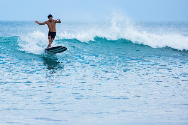 Surfista coreano cavalga um longboard nas ondas azuis