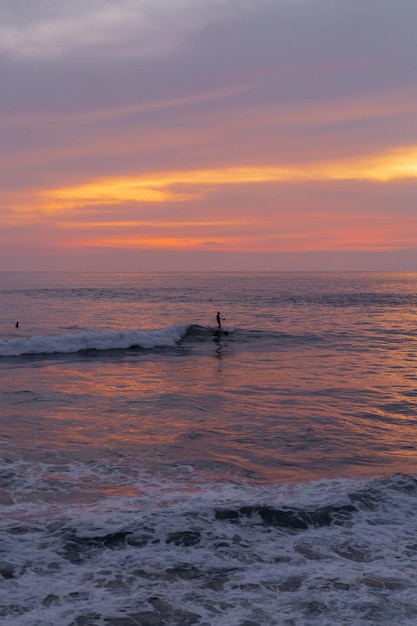 Surfistas pegam ondas ao pôr do sol no oceano. Fundo de surf
