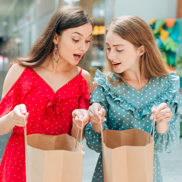 Foto grátis surpreendidos amigos olhando para sacos de compras