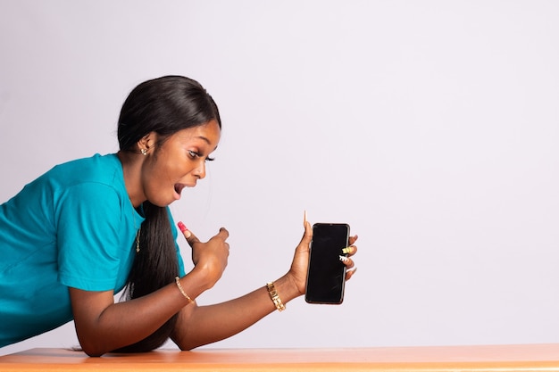 Surpresa olhando bela jovem negra mostrando a tela do telefone