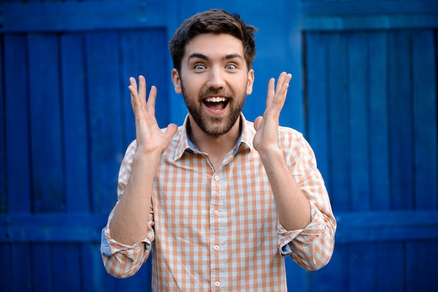 Surpreso jovem bonito na camisa xadrez sorrindo