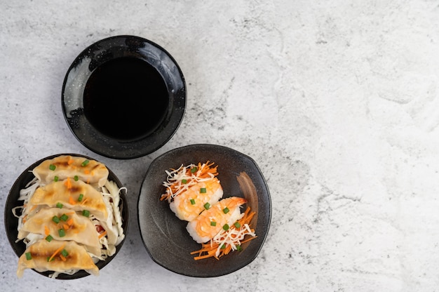 Sushi é um prato com molho sobre um piso de cimento branco.