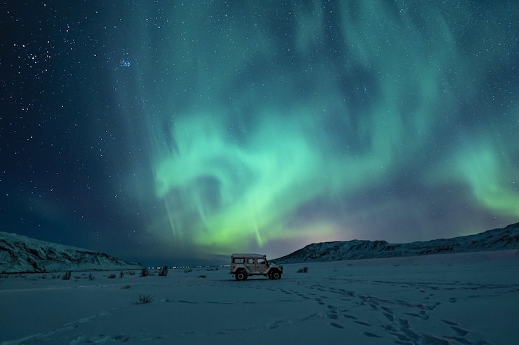 SUV preto em campo coberto de neve sob luzes verdes da aurora