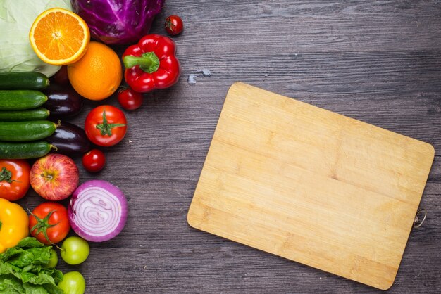 Tabela com vegetais e uma placa de corte