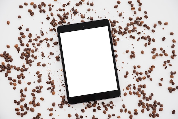 Tablet de vista superior rodeado por grãos de café