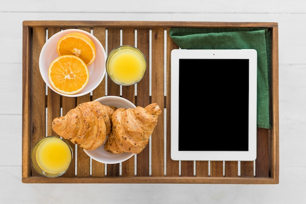 Foto grátis tablet perto de comida na mesa de café da manhã