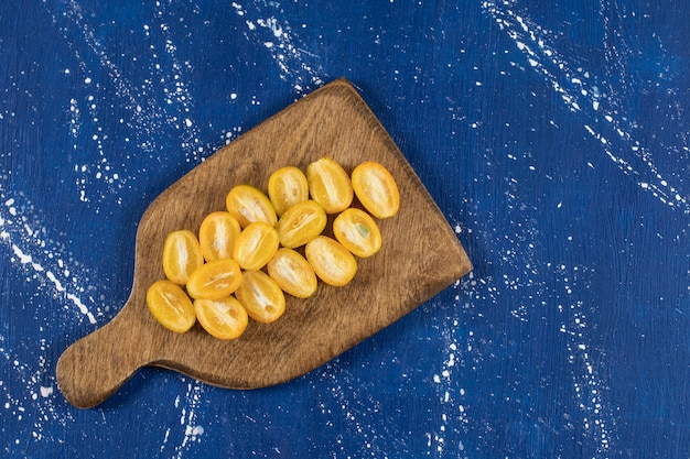 Foto grátis tábua de madeira com fatias de frutas frescas de kumquat na superfície de mármore