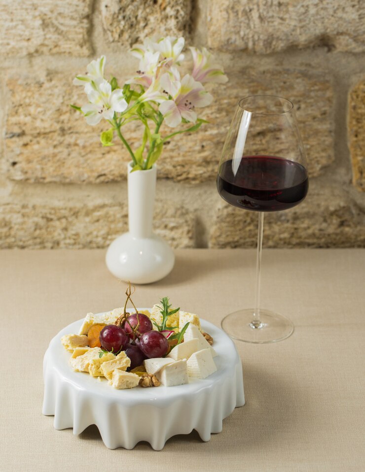 Foto grátis tábua de queijos com um copo de vinho tinto francês