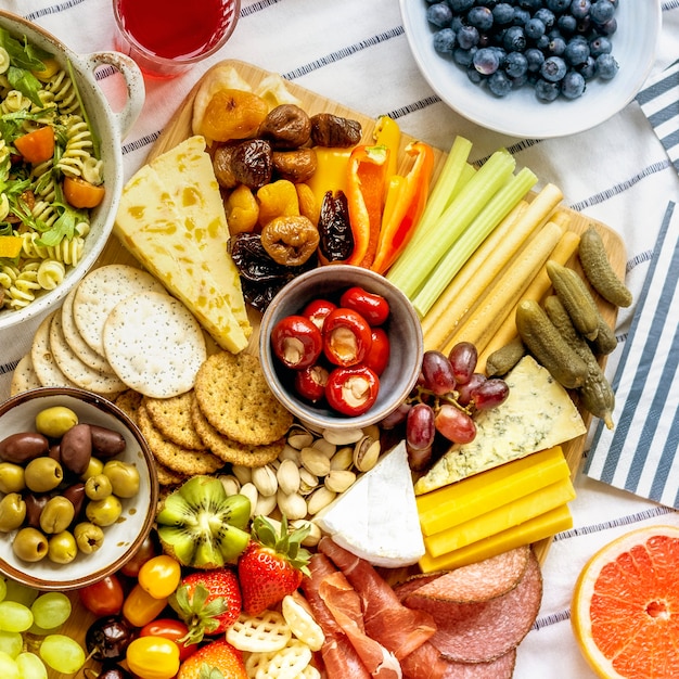 Tabuleiro de charcutaria com charcutaria, fruta fresca e queijos de perto