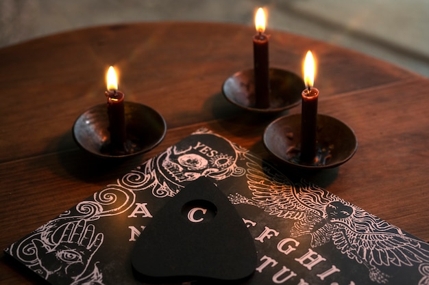 Tabuleiro ouija de alto ângulo e arranjo de velas