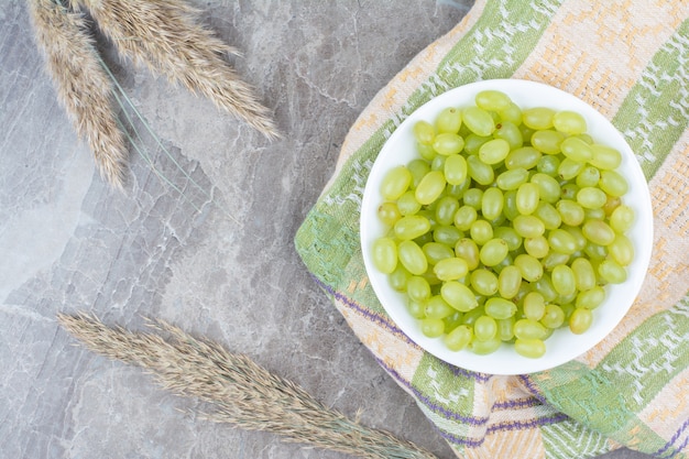 Taça de uvas verdes na toalha de mesa colorida.