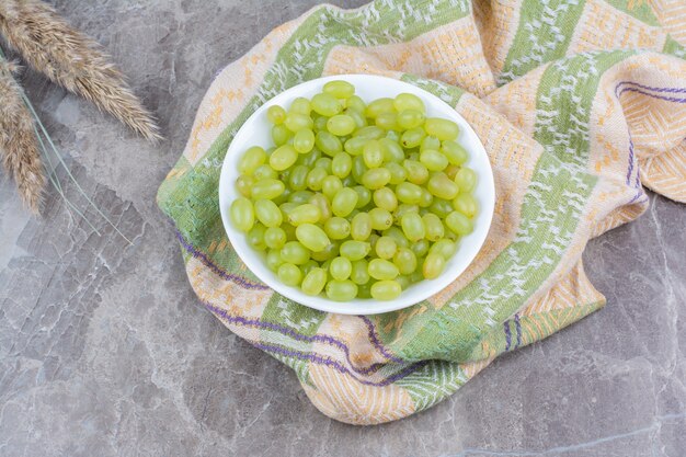 Taça de uvas verdes na toalha de mesa colorida.