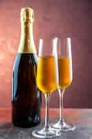 Foto grátis taças de champanhe com vista frontal com garrafa na luz bebida álcool foto cor champanhe ano novo