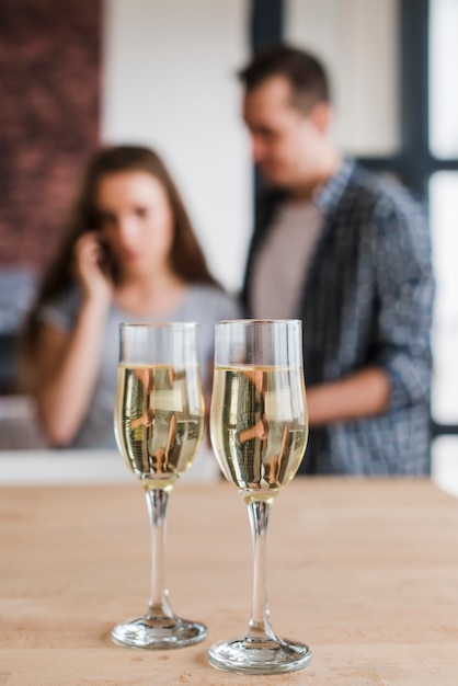 Taças de vinho branco e casal em casa