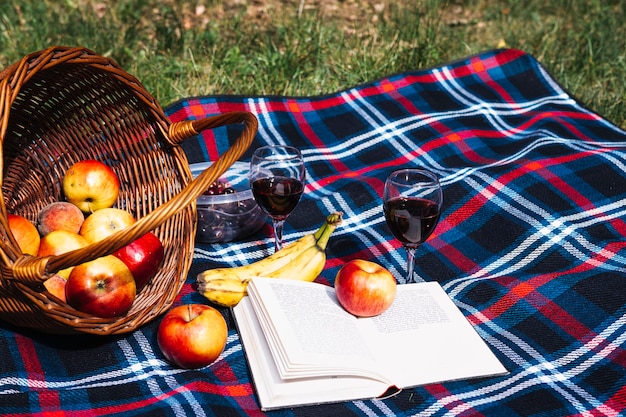 Taças de vinho; maçã; banana e livro no cobertor