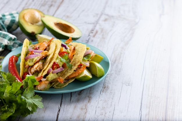 Tacos mexicanos com camarão guacamole e legumes na mesa de madeira