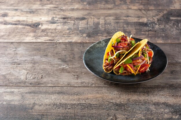 Tacos mexicanos tradicionais com carnes e vegetais na mesa de madeira