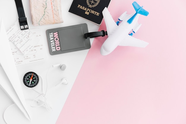 Foto grátis tag do viajante do mundo com passaporte; mapa; bússola; bilhetes; avião de brinquedo e fone de ouvido no fundo branco e rosa