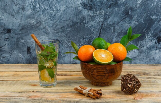 Tangerinas em panela com água detox e canela na placa de madeira