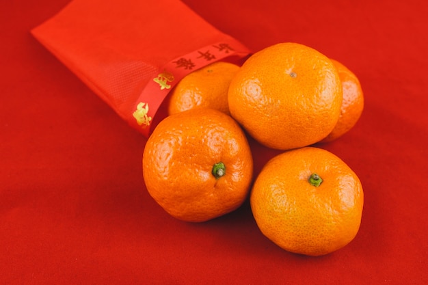 Tangerines empilhadas com um saco vermelho ao lado dele