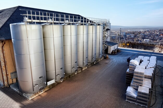 Tanques de armazenamento de vinho de metal com casas de habitação no fundo em uma adega