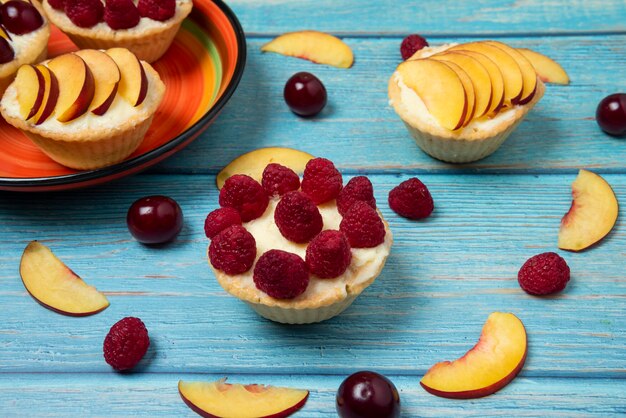 Tartaletes com frutas de verão na mesa de madeira azul