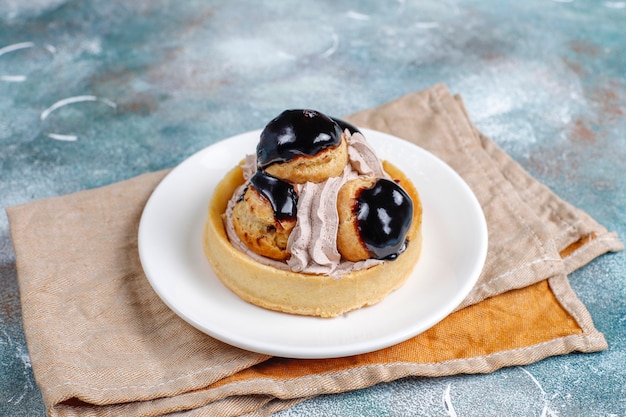 Tarte com profiteroles por cima com chantilly.