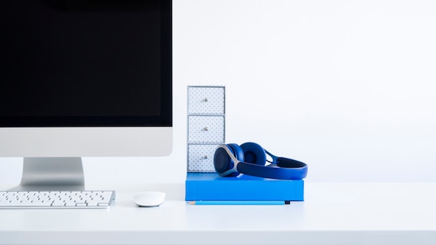Teclado perto de monitor, mouse de computador e fones de ouvido na mesa