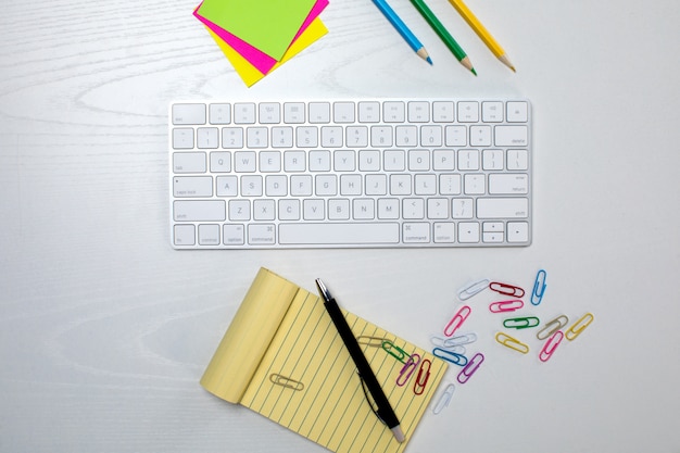 Teclado sem fio e bloco de notas amarelo em cima da mesa