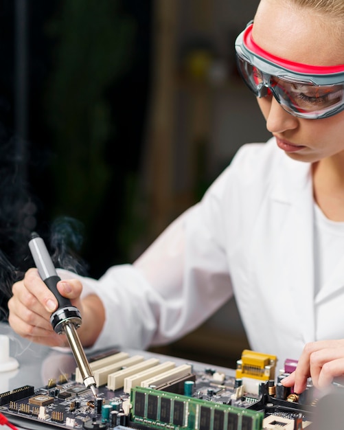 Técnica feminina com ferro de solda e placa eletrônica