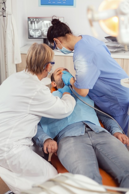 Técnica sênior verificando dentes e examinando paciente doente