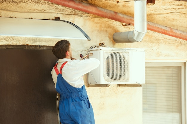 Foto grátis técnico de hvac trabalhando em uma peça de capacitor para unidade de condensação