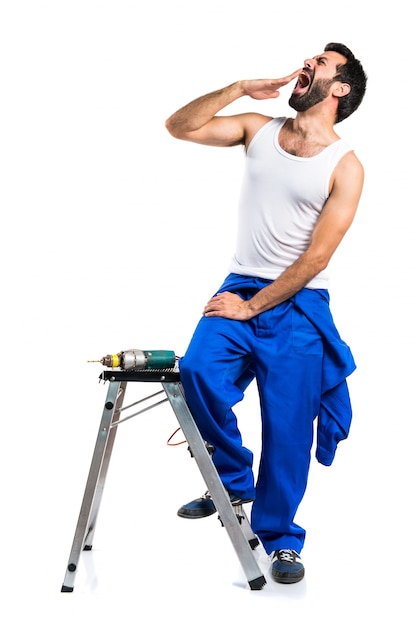 Técnico elétrico jovem com uma broca bocejando