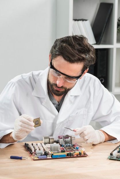 Técnico segurando o chip de computador com placa-mãe na mesa de madeira